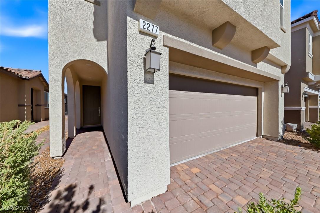 Image 4: A welcoming arched entryway and paved driveway enh
