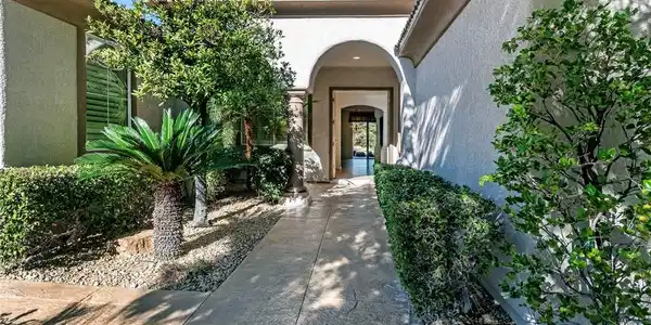 Image 2: An arched entry porch leads past desert landscapin