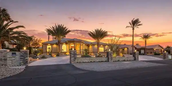 Image 3: Palm trees frame the curved driveway and paved ent