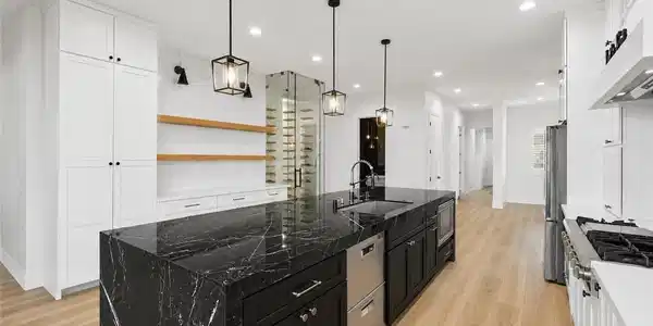 Image 4: A well-lit kitchen features a dramatic black marbl