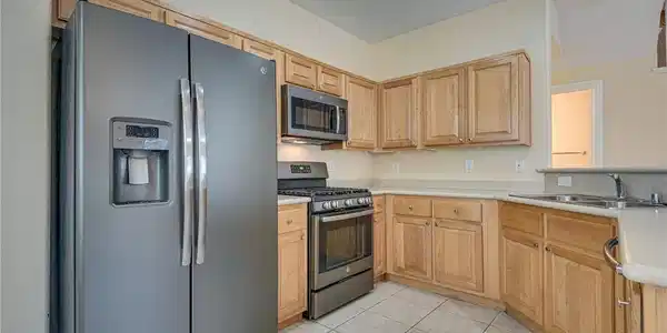 Image 2: Natural wood cabinetry and neutral tile flooring a