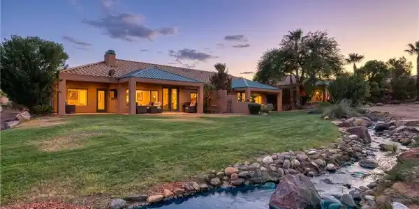 Image 2: Lush green lawns and a stone-lined stream frame th