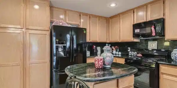 Image 3: Ample wooden cabinetry and stone counters define t