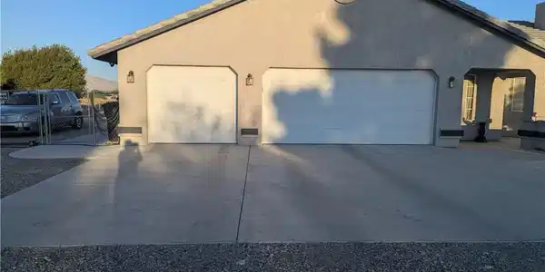 Image 2: A well-maintained concrete driveway leads to a thr