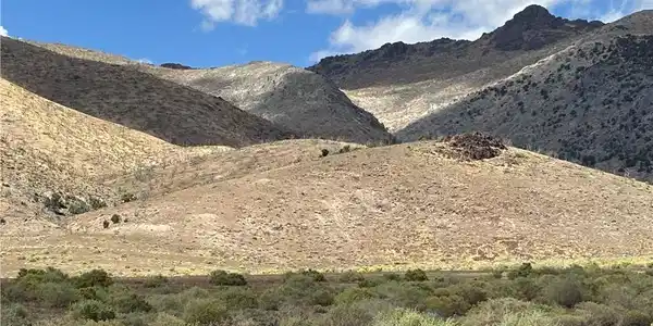 Image 2: Dramatic mountain ridges rise above the desert bru