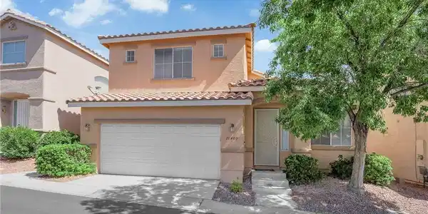 Image 3: A well-maintained stucco home with a tile roof and