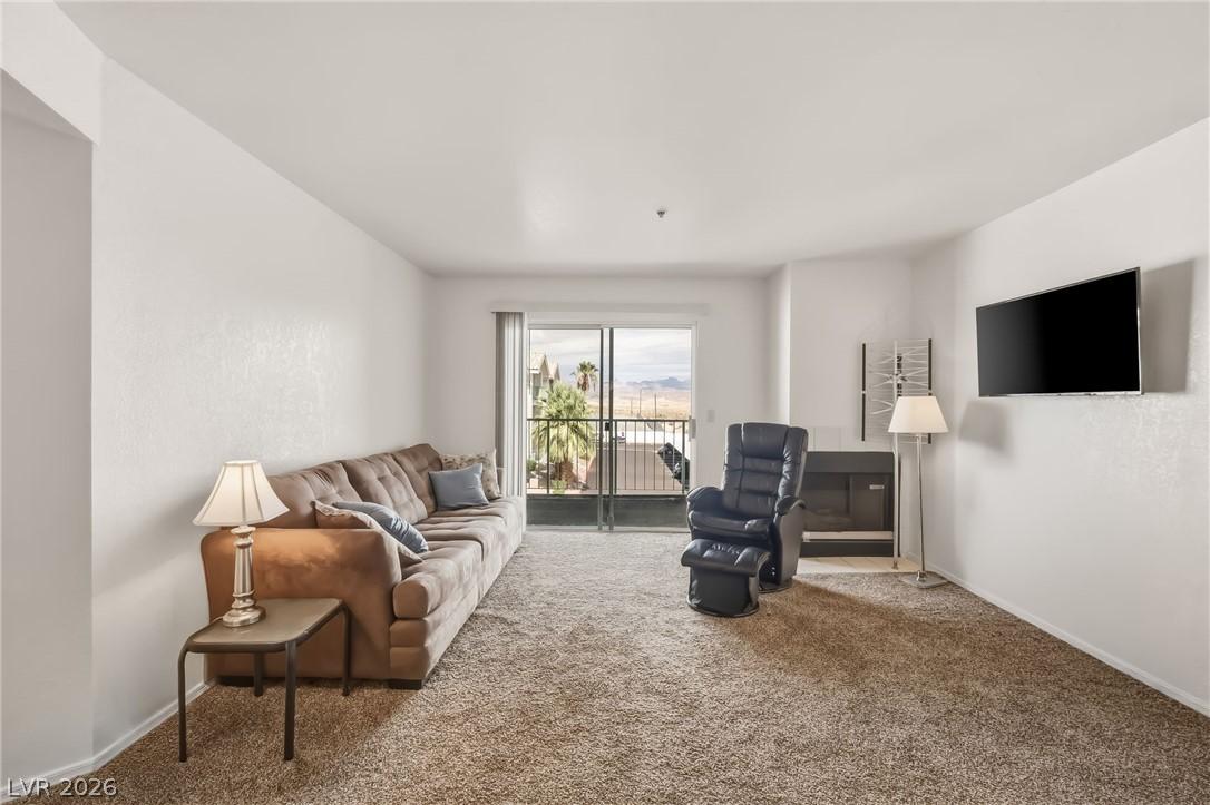 Image 3: A spacious living area with carpeted floors and a