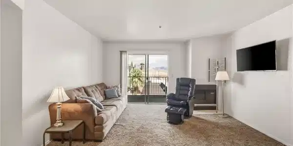 Image 3: A spacious living area with carpeted floors and a