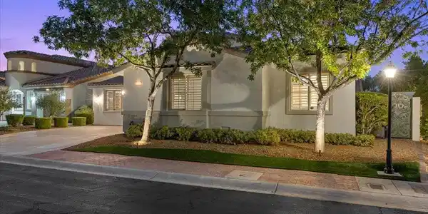 Image 3: Mature trees frame the elegant stucco exterior and