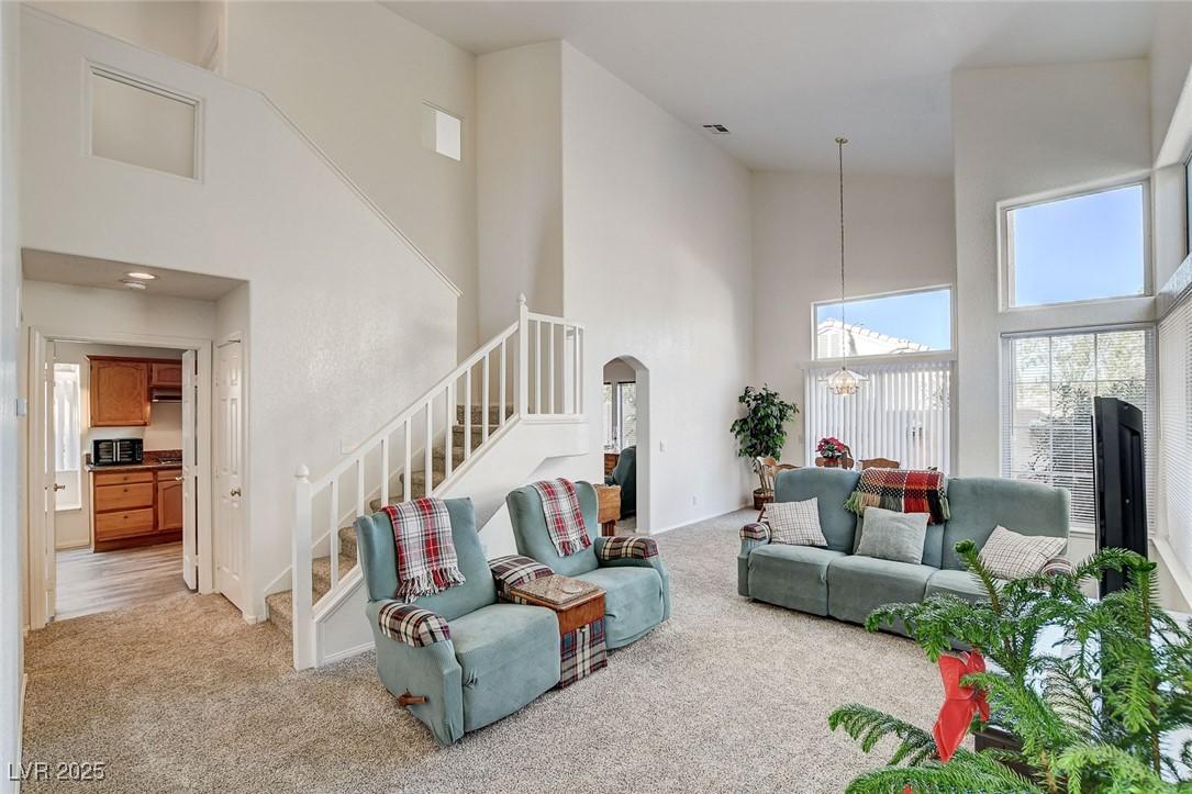 Image 3: Living room with a high ceiling, light carpet, sta