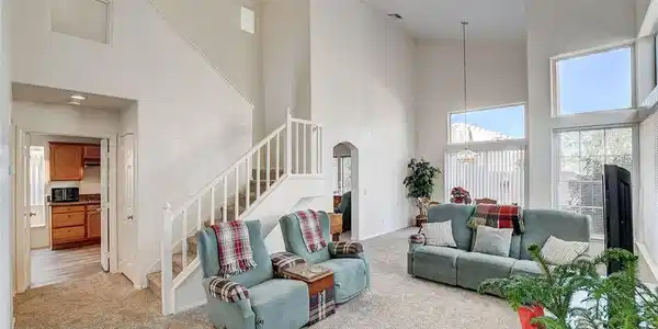 Image 3: Living room with a high ceiling, light carpet, sta