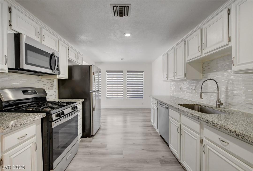 Image 4: A pristine kitchen showcasing white cabinetry, gra