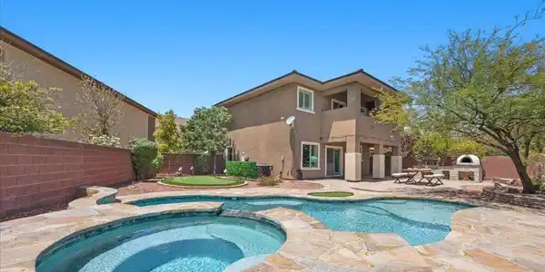 Image 2: Natural stone decking surrounds the sparkling pool