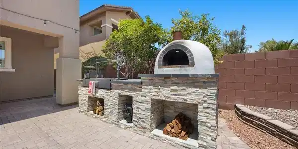 Image 4: An outdoor kitchen with a stone-clad wood-fired pi