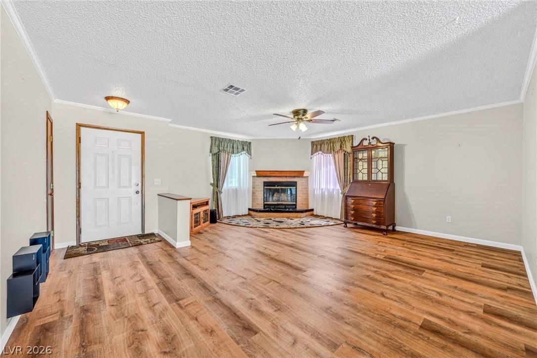 Image 3: Warm wood-look flooring and a brick fireplace crea