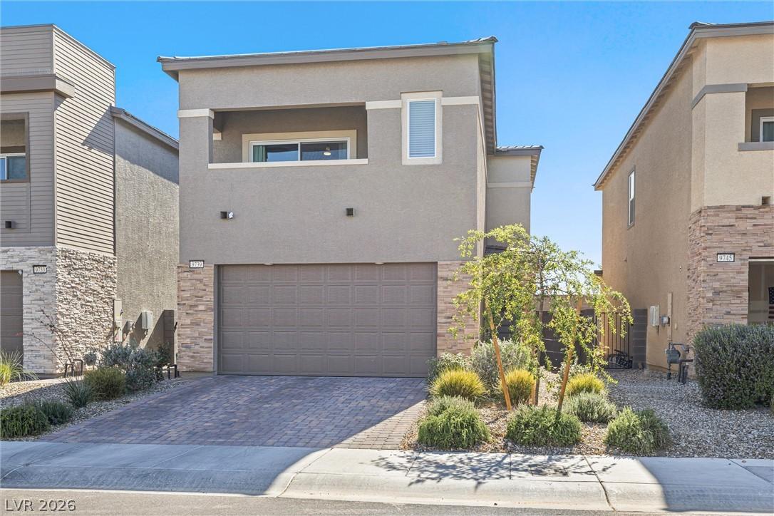 Image 2: A modern facade with a paver driveway, accented by
