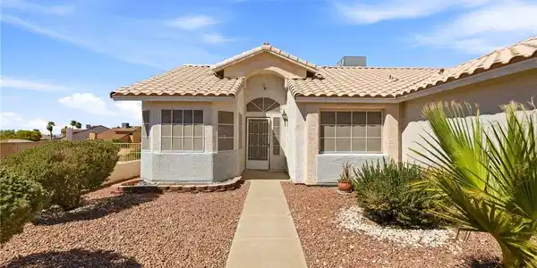 Image 2: Desert landscaping and a concrete walkway lead to