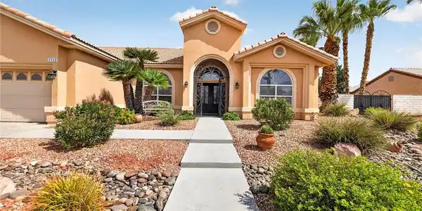 Image 2: Desert landscaping and a concrete walkway lead to