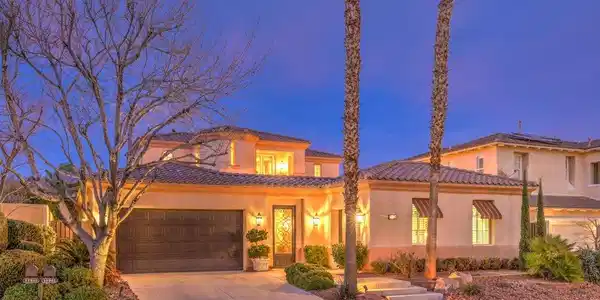 Image 2: Illuminated at dusk, this home boasts an elegant t