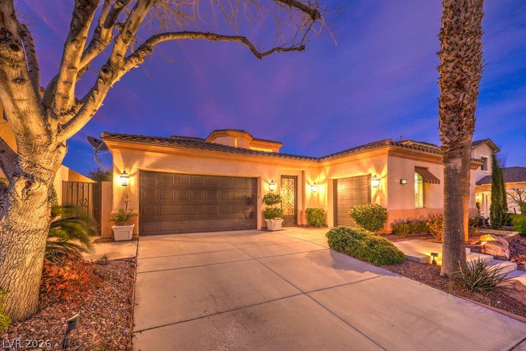 Image 4: Illuminated at dusk, a charming stucco residence b