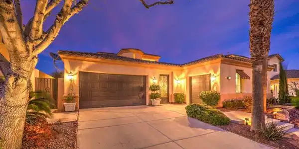 Image 4: Illuminated at dusk, a charming stucco residence b