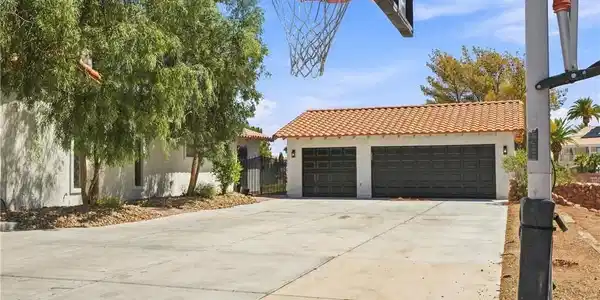 Image 2: A spacious concrete driveway leads toward a detach