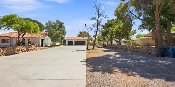 Image 3: Mature trees frame a wide concrete driveway leadin