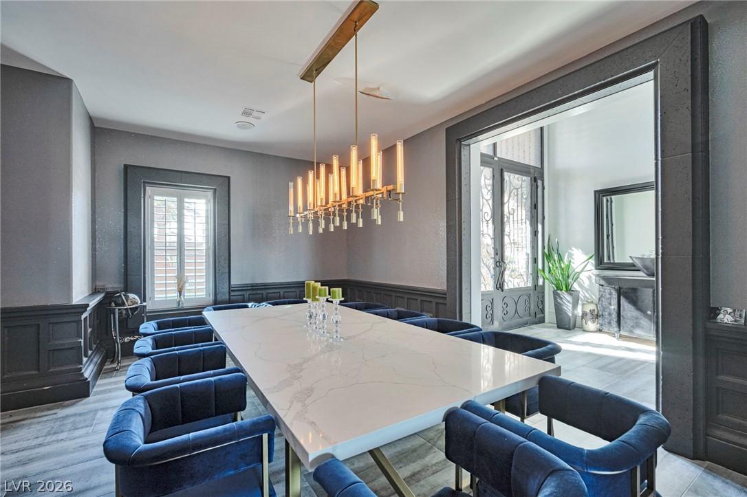 Image 4: A striking linear chandelier illuminates a grand d