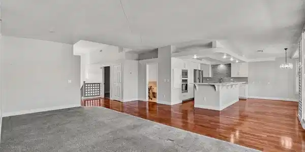 Image 3: Rich wood flooring connects the expansive living a