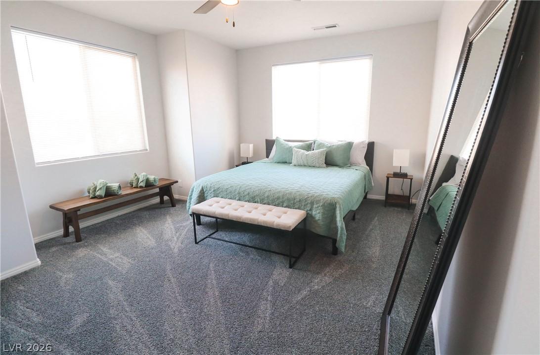 Image 4: Well-lit master bedroom with plush carpeting and a