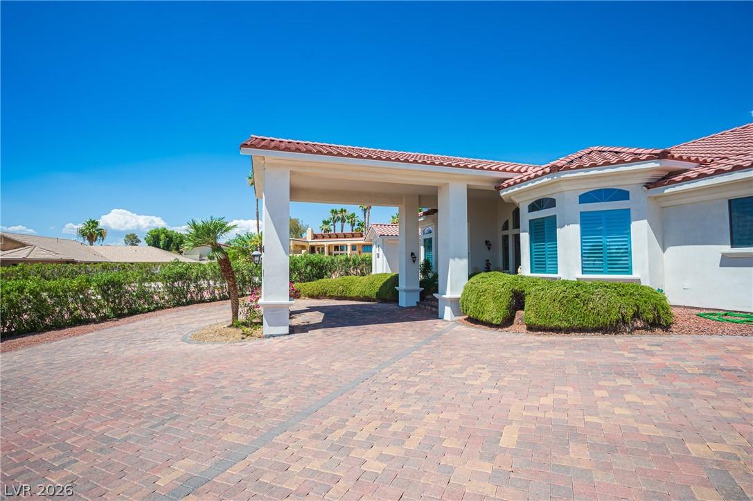 Image 3: A spacious paver driveway and covered entry lead t