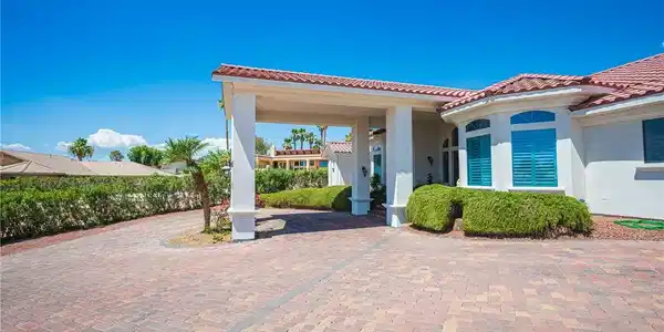 Image 3: A spacious paver driveway and covered entry lead t