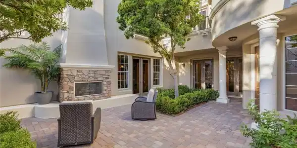Image 2: An inviting stone fireplace anchors this paved cou