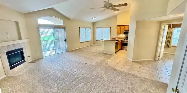 Image 3: A spacious living area with vaulted ceilings, a co