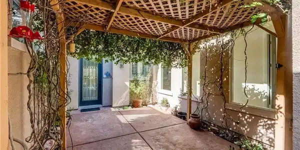 Image 4: A wooden lattice pergola shades a concrete courtya