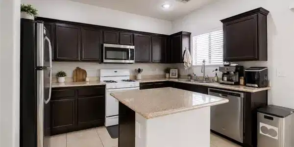 Image 3: Granite counters and dark wood cabinetry provide a