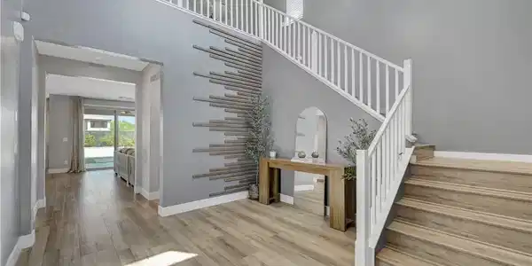 Image 3: An open stairway and natural wood flooring define