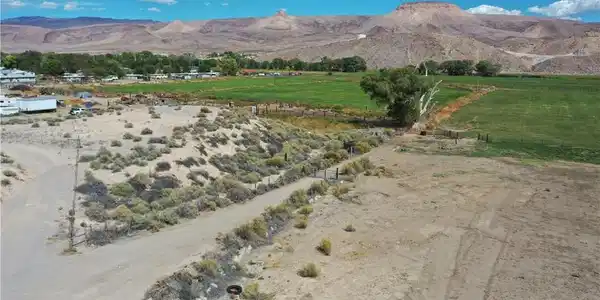 Image 3: Rugged terrain meets green pastures set against a