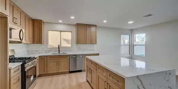 Image 4: Gleaming stone countertops and warm wood flooring