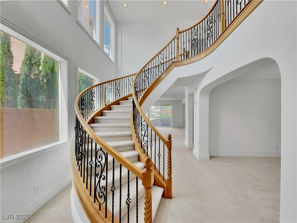 Image 2: Stairway with carpet flooring, a towering ceiling,