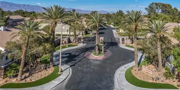 Image 2: A gated entry lined with palm trees leads into a p