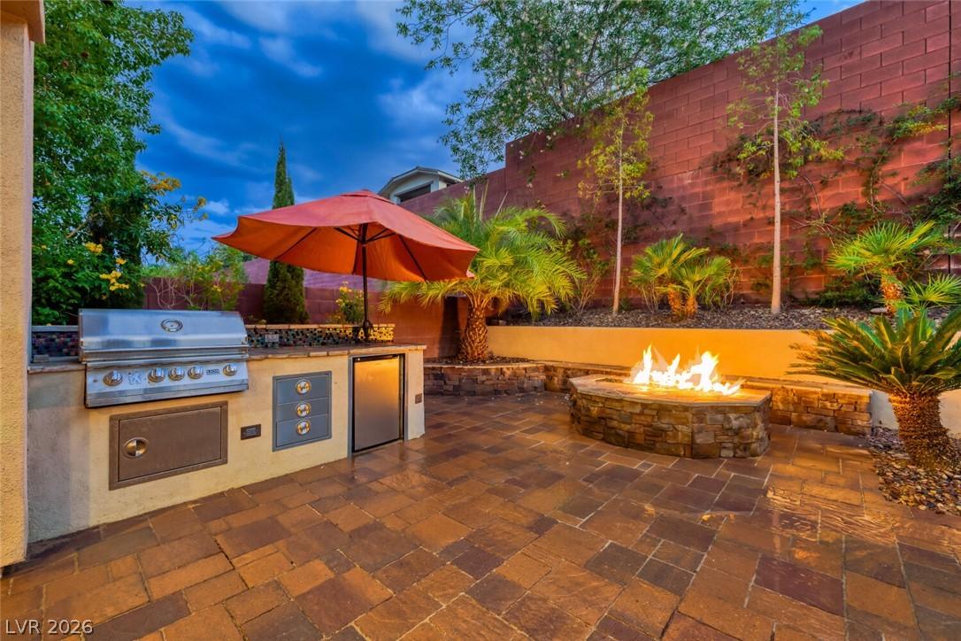 Image 3: An inviting outdoor kitchen and fire pit create a