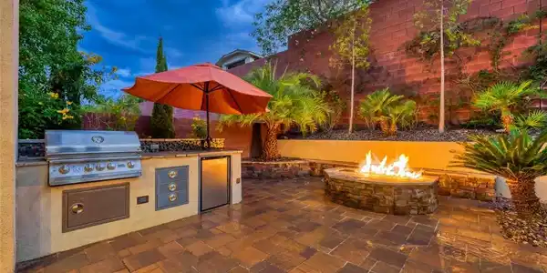 Image 3: An inviting outdoor kitchen and fire pit create a