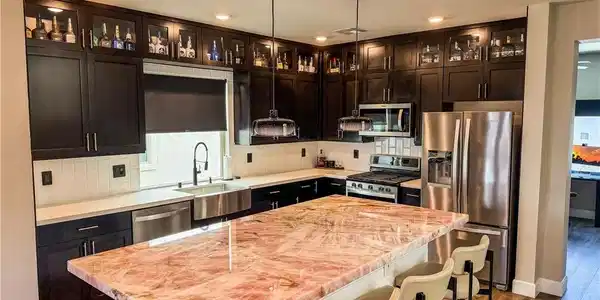 Image 4: Richly toned cabinetry and highly polished stone s