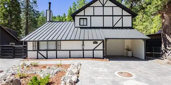 Image 2: A striking Tudor-style home with a modern metal ro