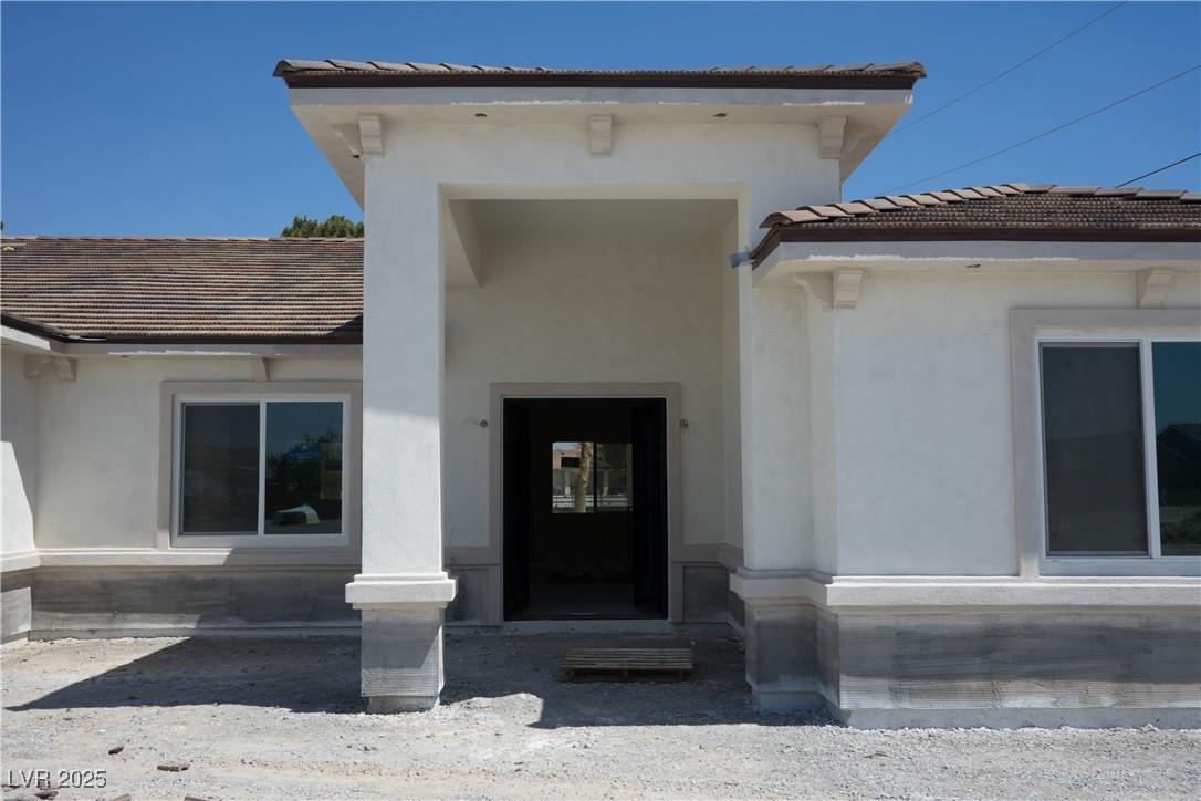 Image 2: View of exterior entry with stucco siding and a ti