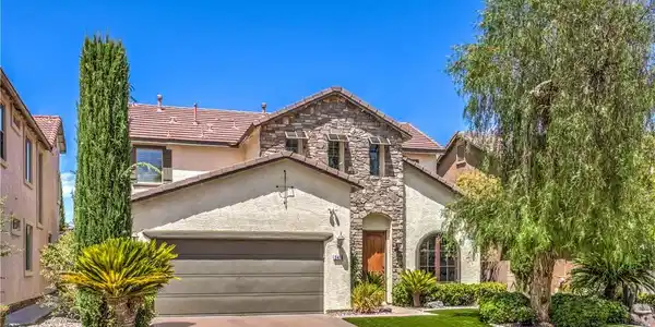 Image 2: This two-story residence features a stone and stuc