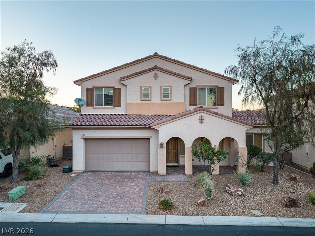 Image 1: A charming stucco residence with a brick paver dri