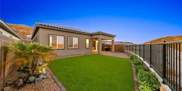 Image 4: Manicured green lawn and a covered back patio defi