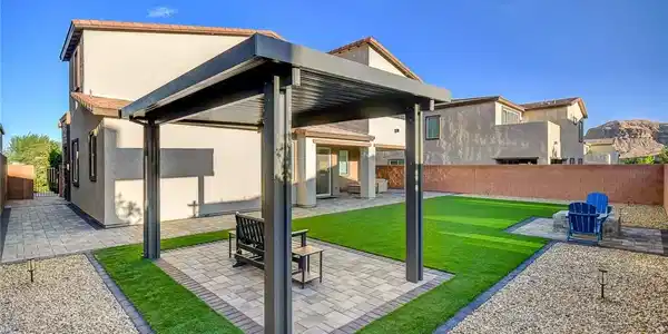 Image 2: A structured metal pergola shades a paved patio in